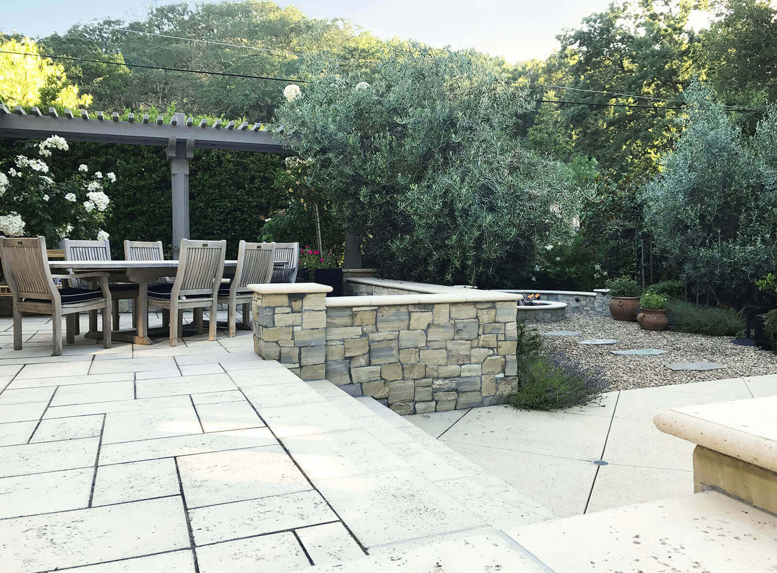 Travertine-tiled terraced patio with gravel area and Mediterranean planting