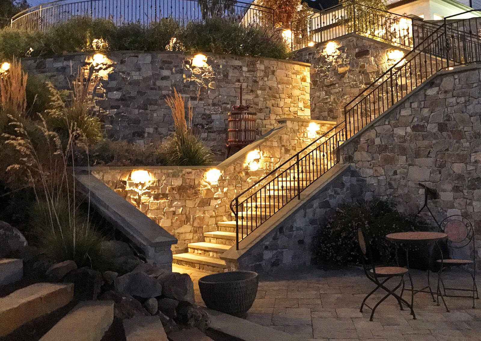 Accent lighting on edge of upper wall, with well-lit warm lighting on stairs leading from bottom deck to house