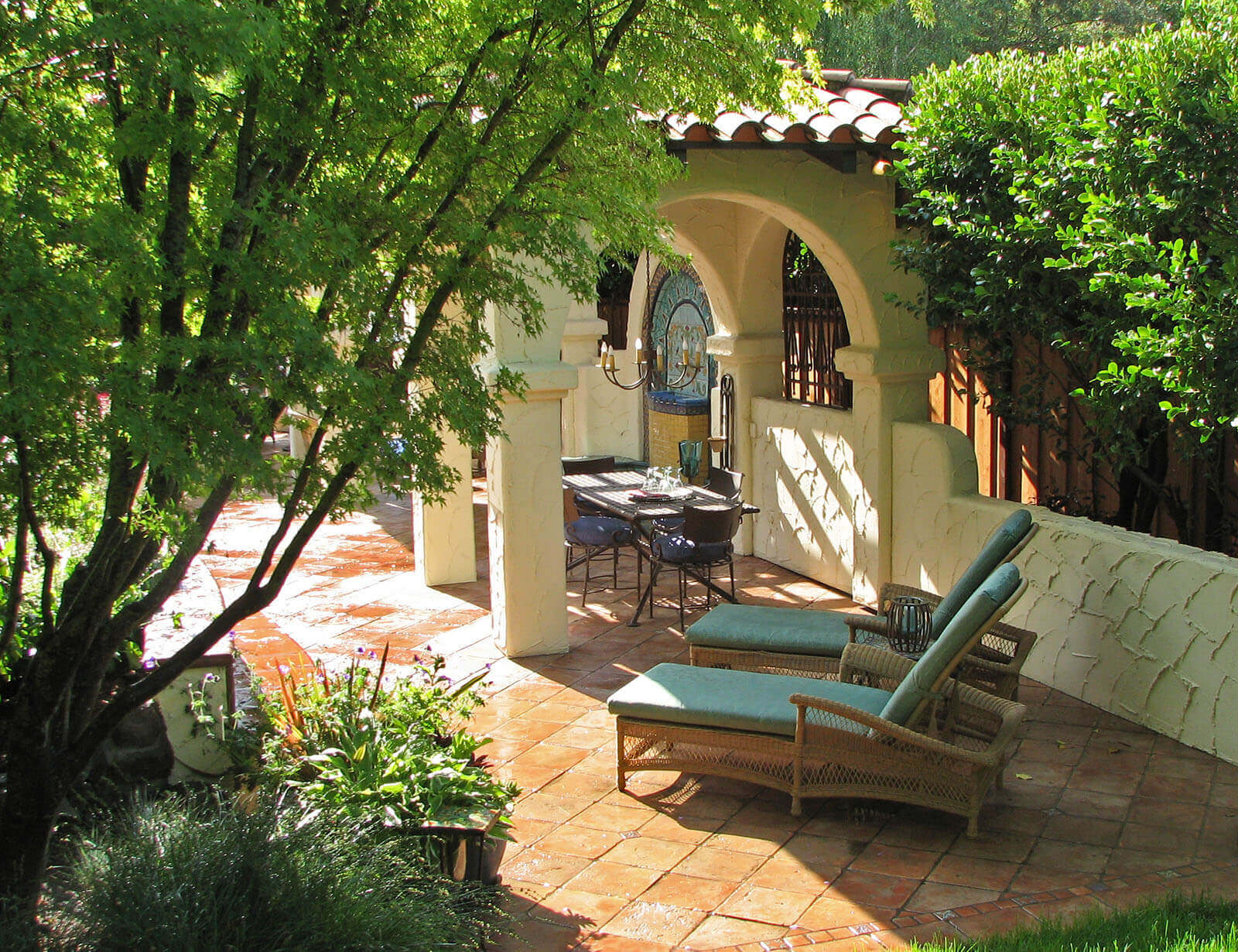 Shady and secluded Saltillo-tiled patio with lounge chairs and Mission-style pergola