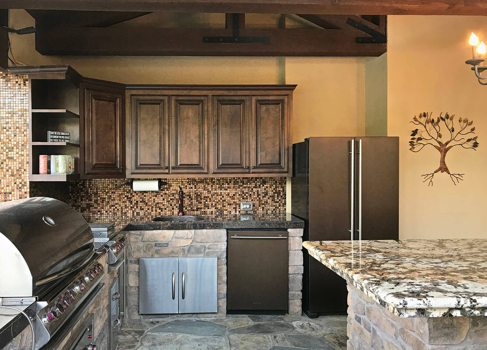 Colorful marble kitchen island with indoor grilling area, wooden cabinets and mosaic backsplash