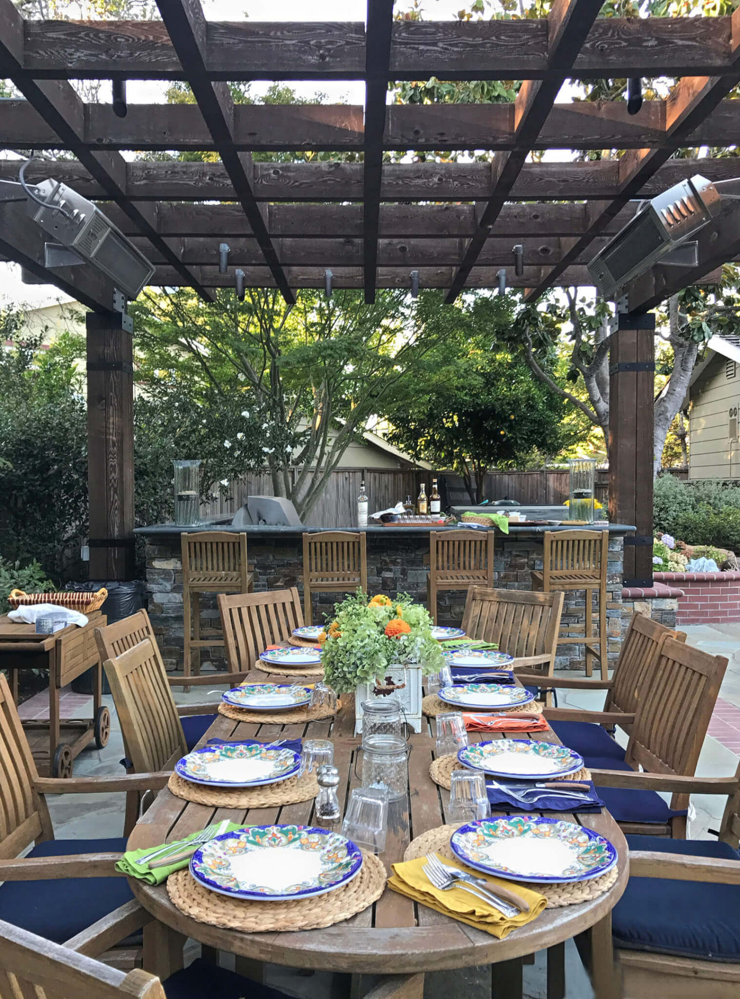 Outdoor dining area under pergola colorfully set for a summer dinner