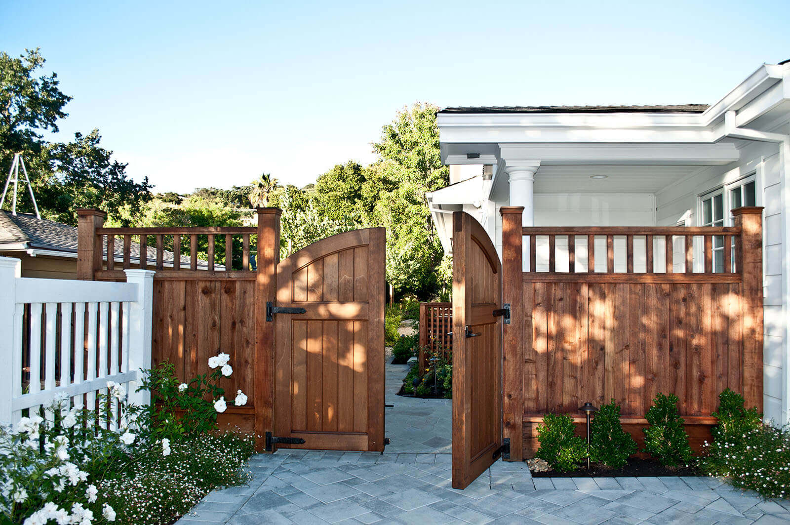 Redwood double gate with white roses opens to back yard
