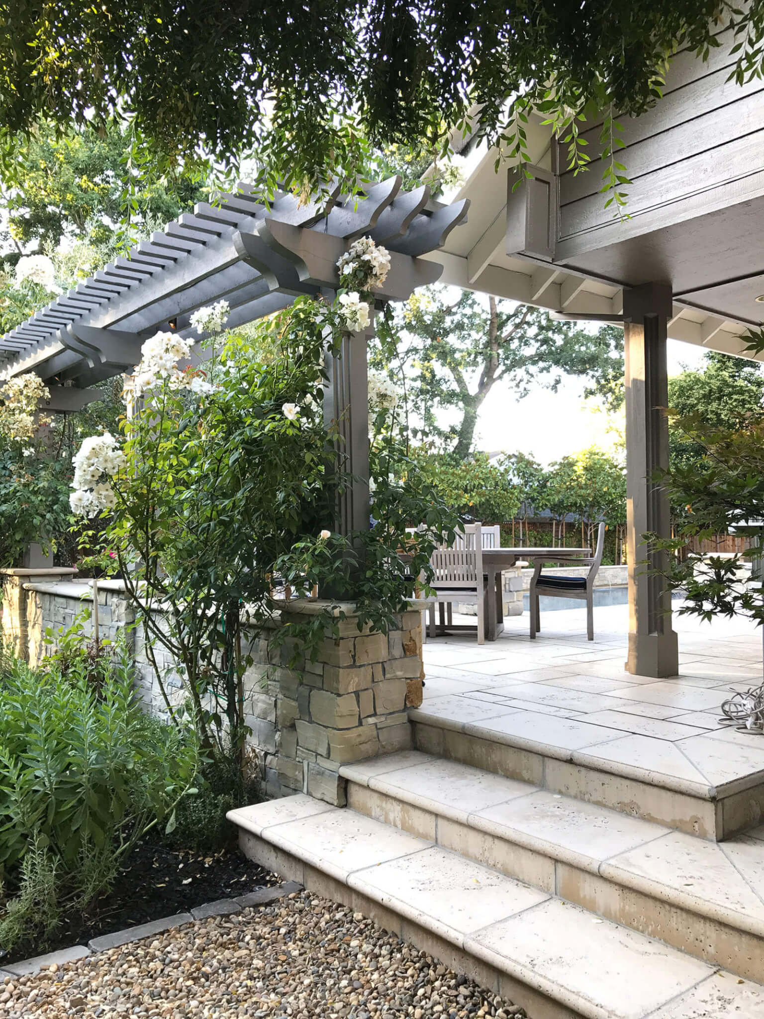 Raised stone tile patio with wrapping structures leading to gravel path below