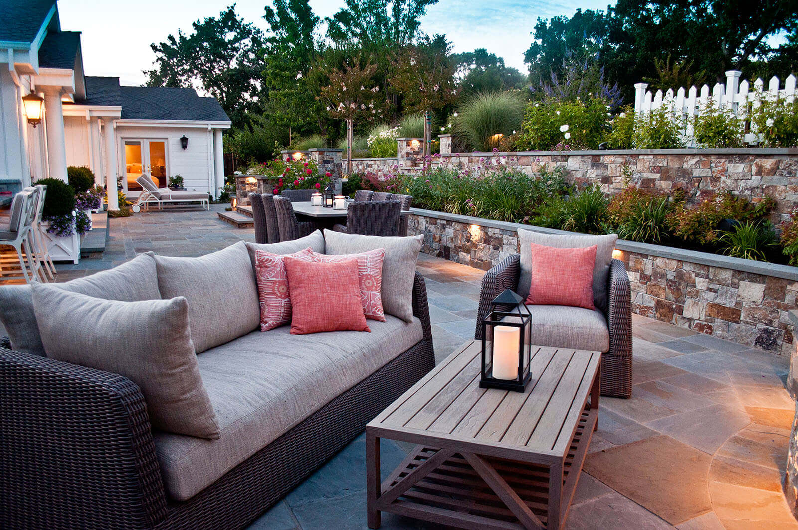Outdoor patio with lighting on lower walls, fixtures on posts, and lights near stairs, candles are used as well