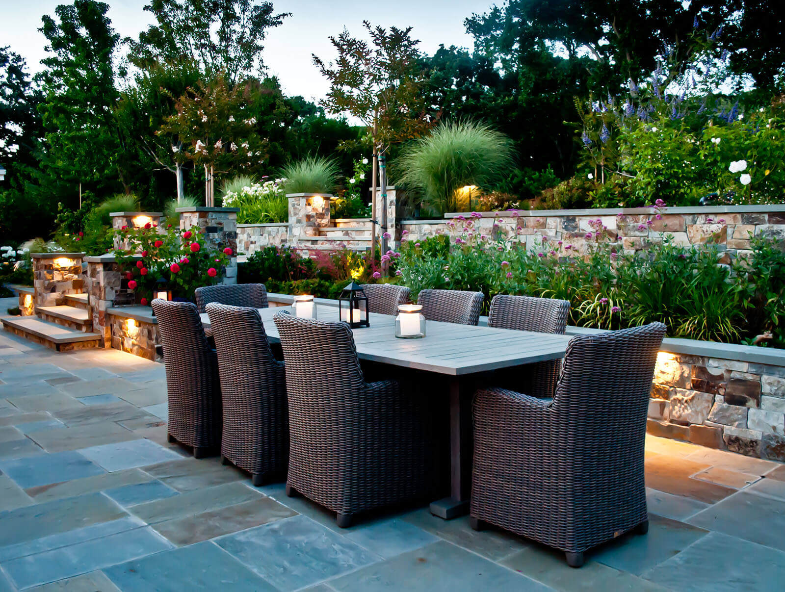 Open laid stone patio with outdoor furniture and staged garden - ambient lighting
