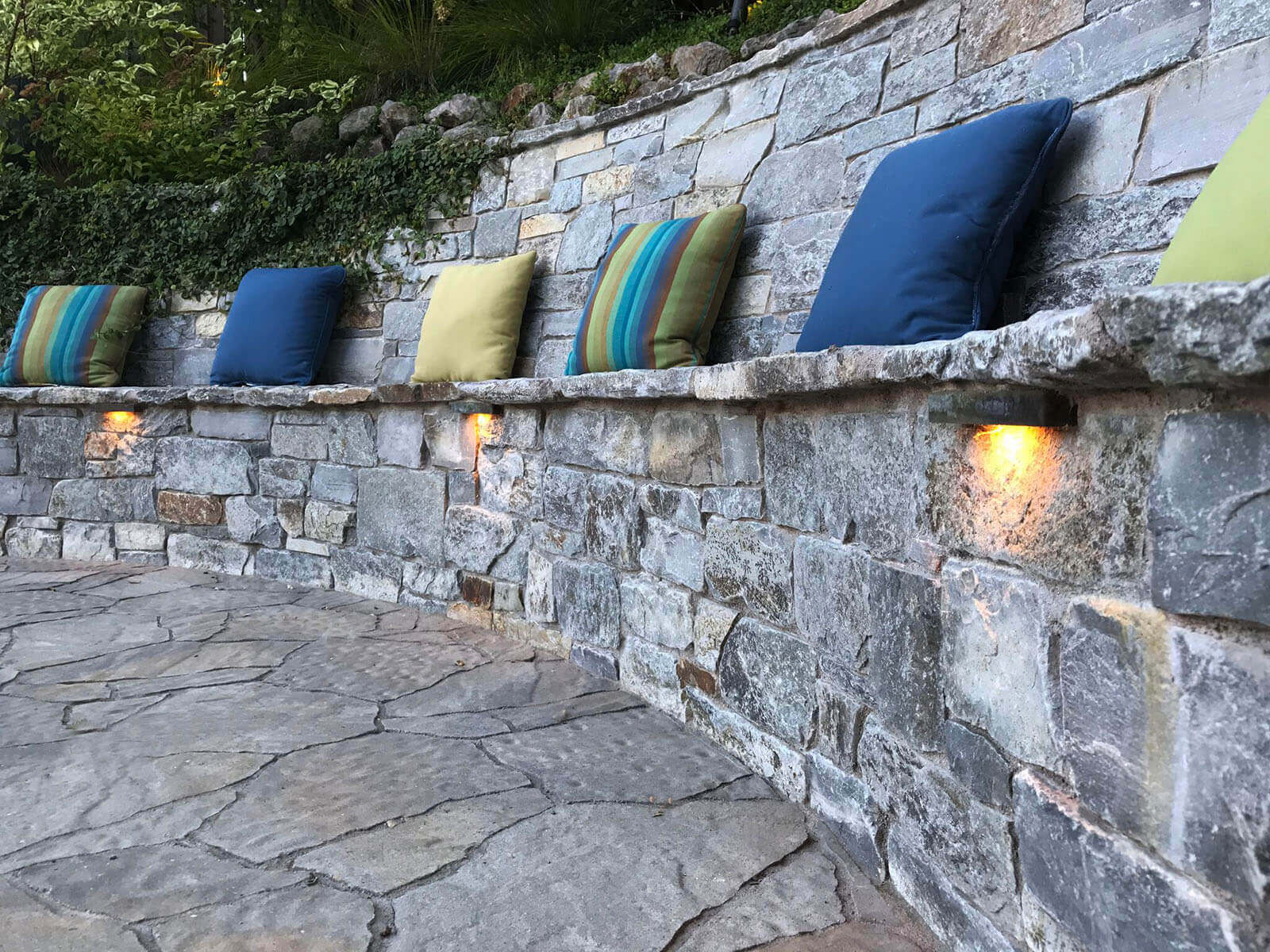 Accent lighting on wrapped stone bench structure with pillows