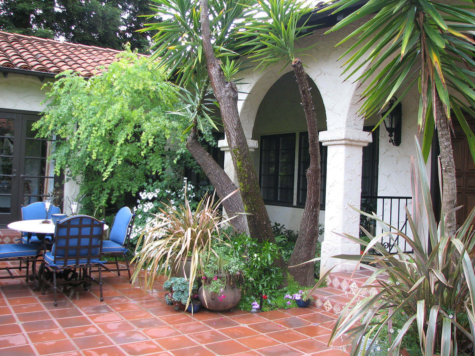 Saltillo-tiled courtyard with Mission-style arches and tropical planting
