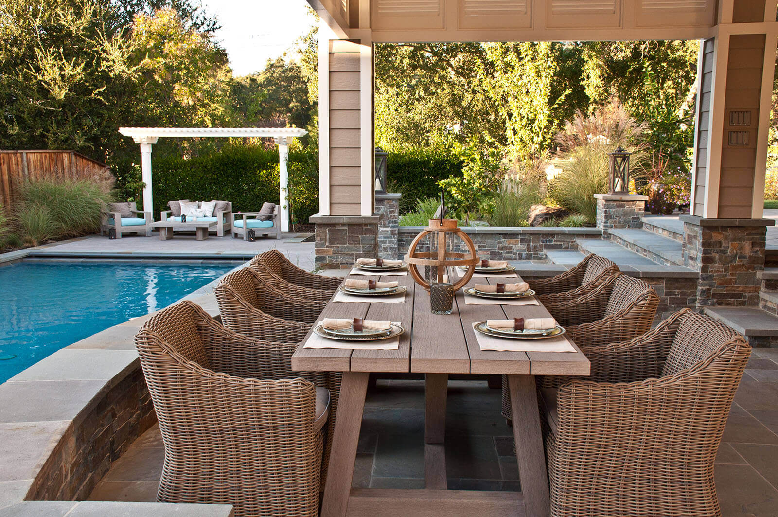 Terraced bluestone patio and outdoor dining overlooks pool and poolside seating area