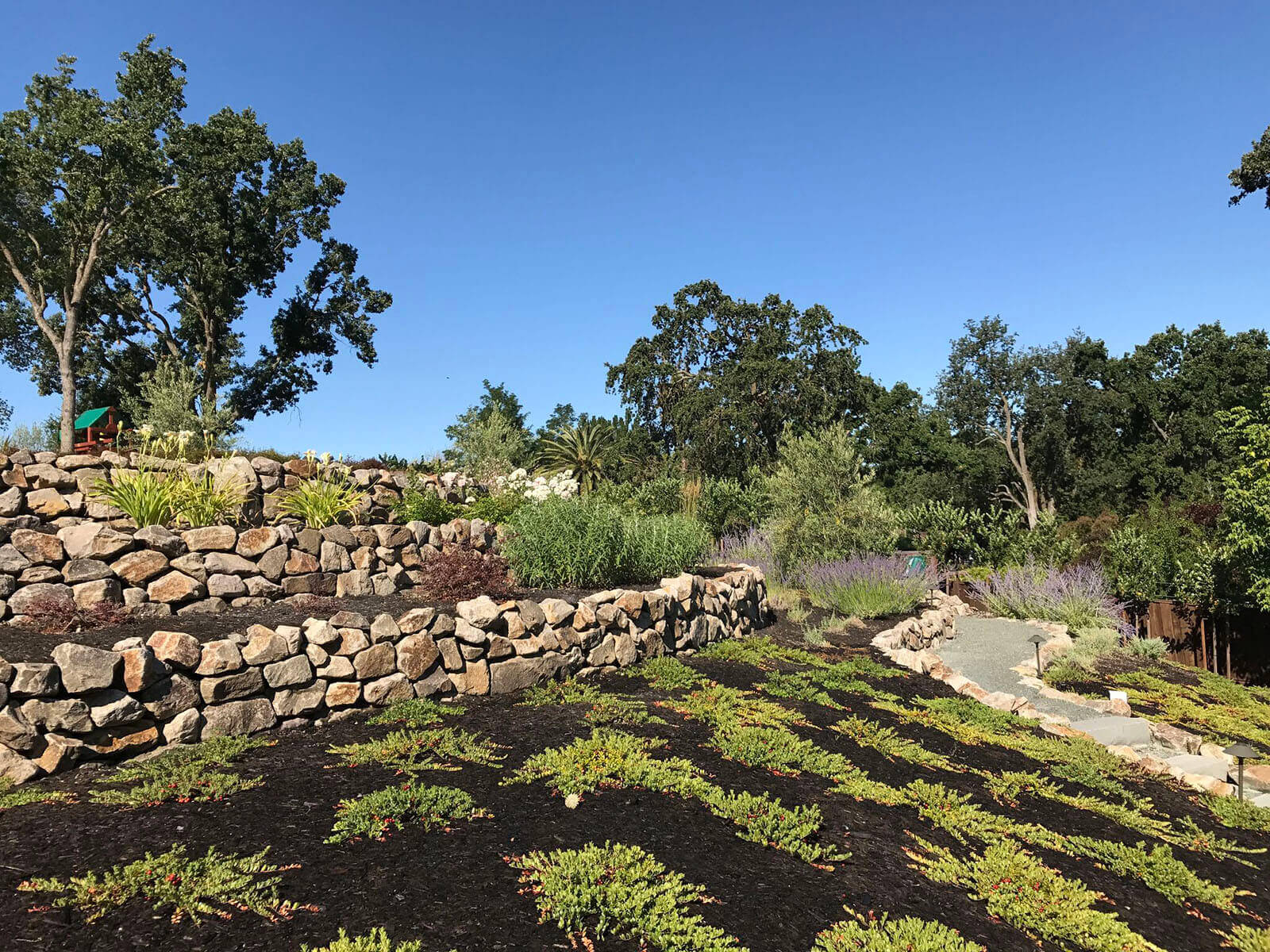 Multilevel gardening areas with rock walls and gravel pathways