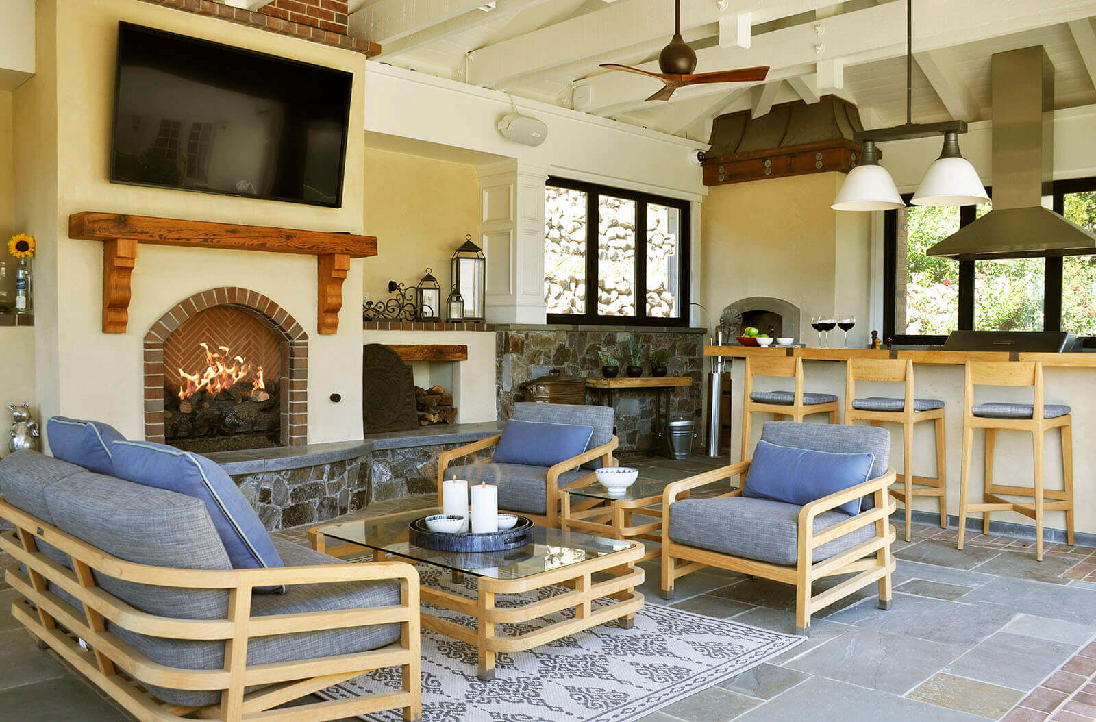 Indoor/outdoor cabana features a fireplace with lounge adjacent to bar