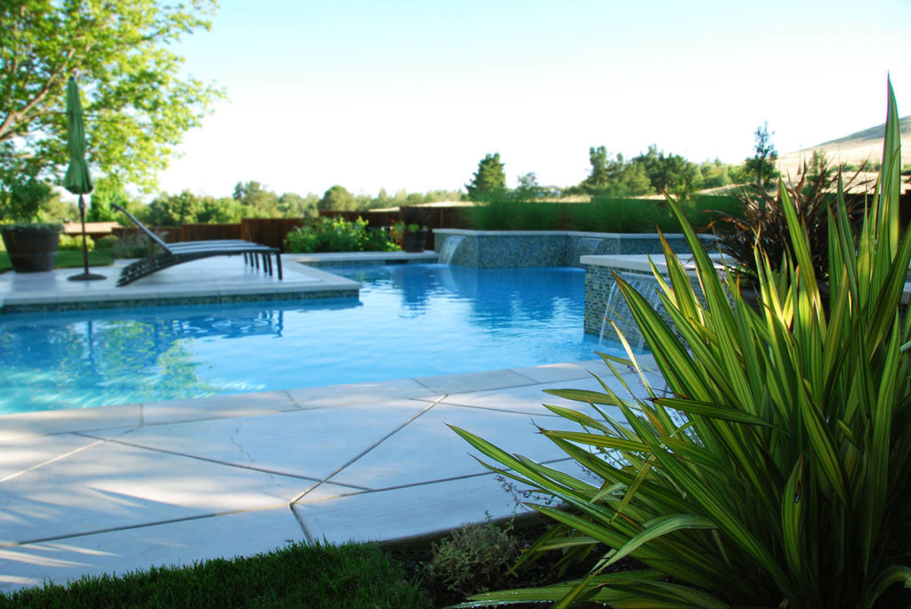Sheer descent fountains cascade into a geometric pool with contemporary landscaping