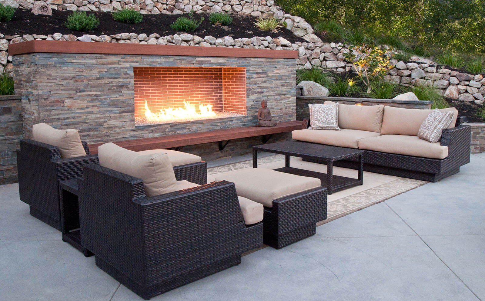 Contemporary bluestone and brick fireplace with crushed glass, wooden mantel and hearth, and outdoor lounge