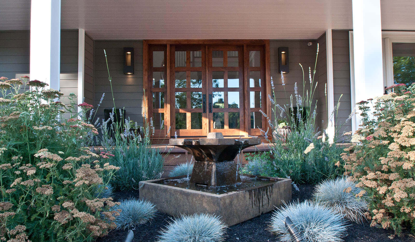 Centerpiece fountain with blue, green, and white grasses and flowers in front of glass ranch doors