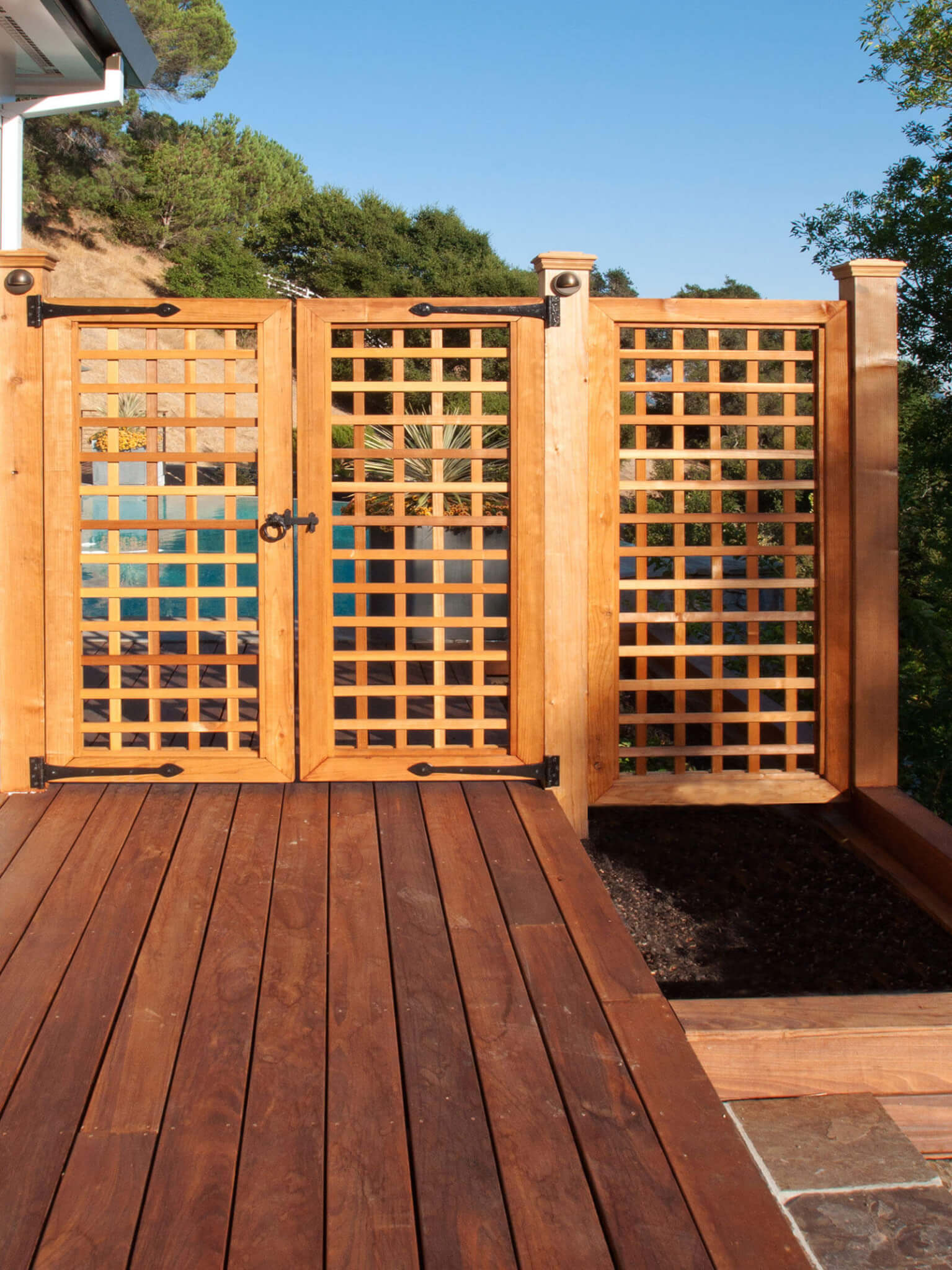 Tall wood lattice gate with wrought iron fixtures on a wood deck