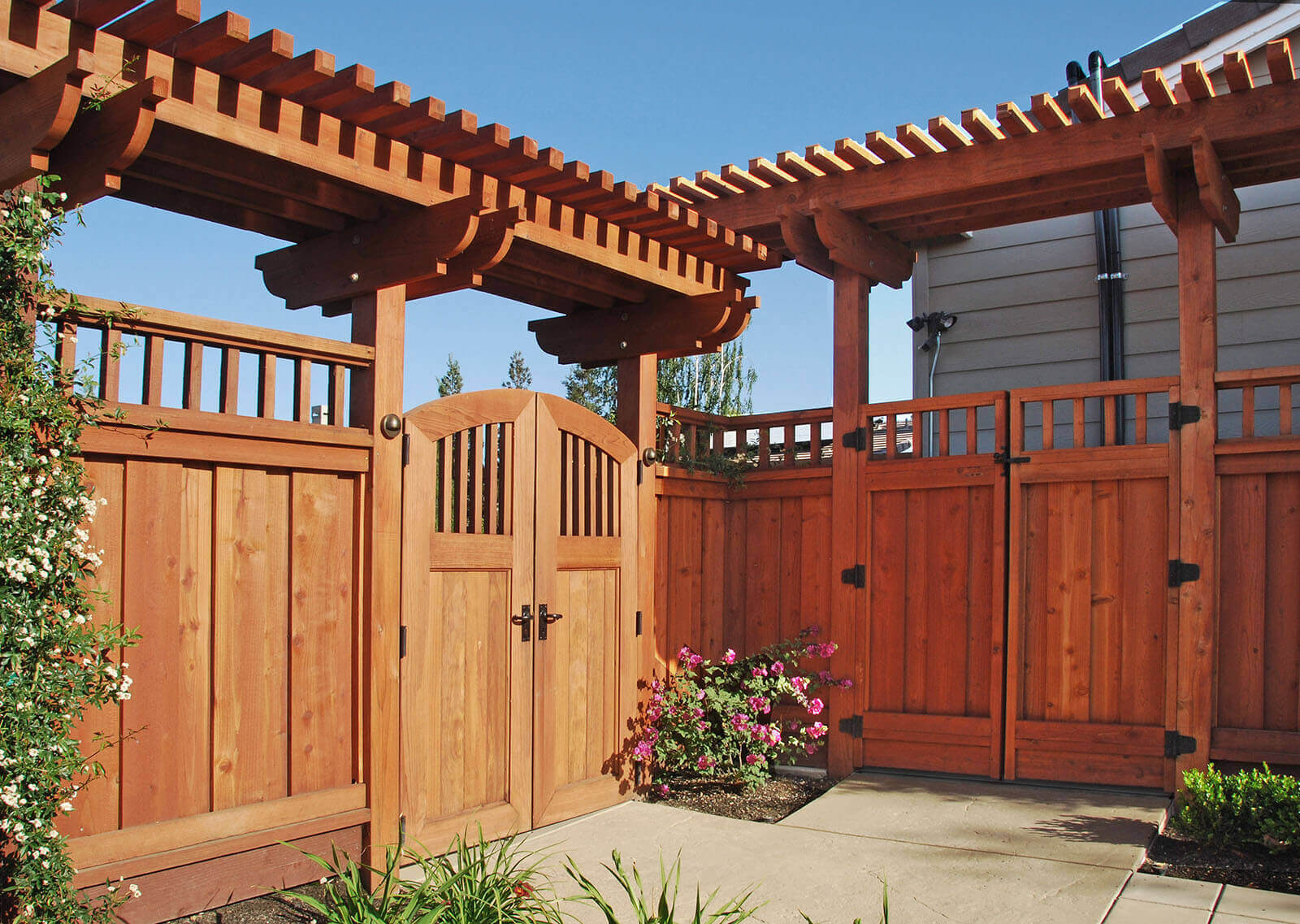 Tall redwood privacy fence with custom arbors and wrought iron hardware