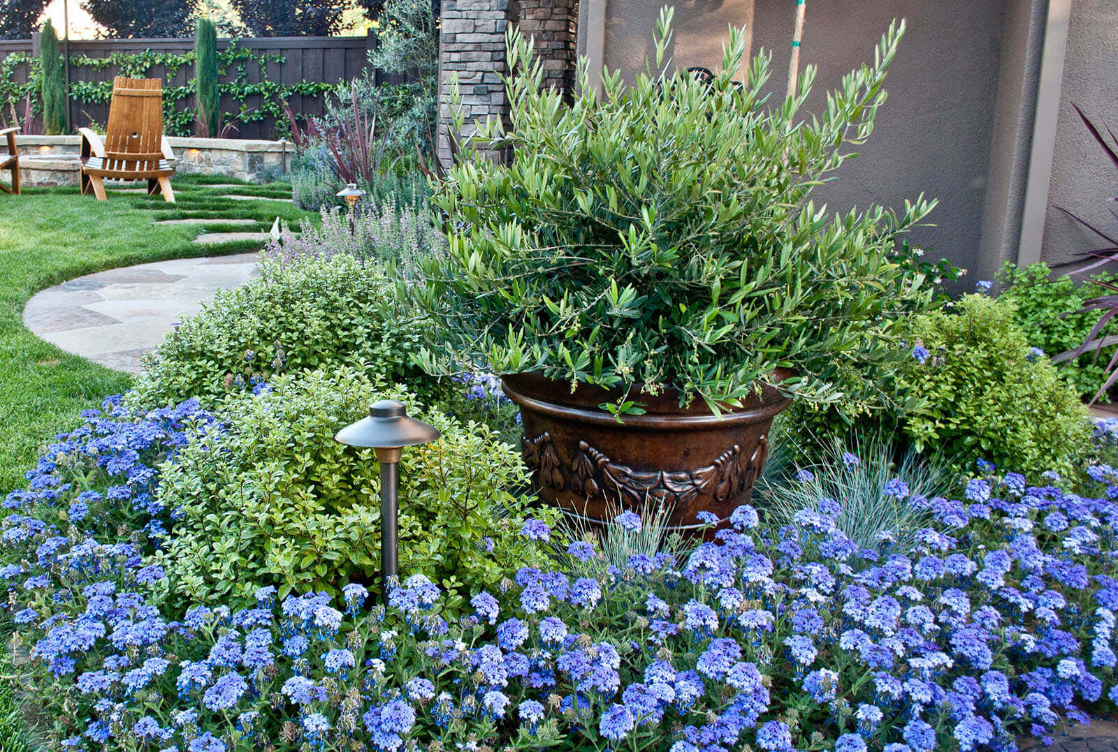 Accented ceramic pot among clustered blue flowers and greenery