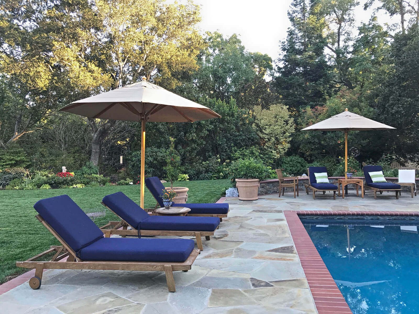 Brick-lined pool set in stone tiled patio with cobalt poolside lounges
