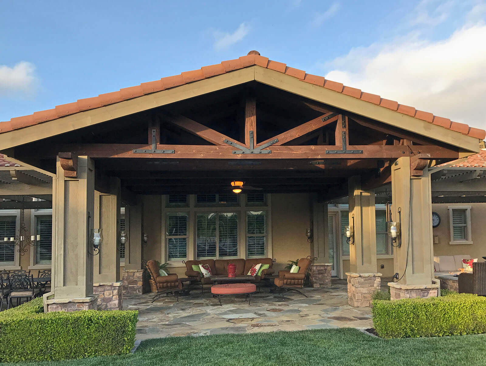 Pergola with Mission-style tile roof, wood rafters and columns shelters an outdoor lounge on a flagstone patio