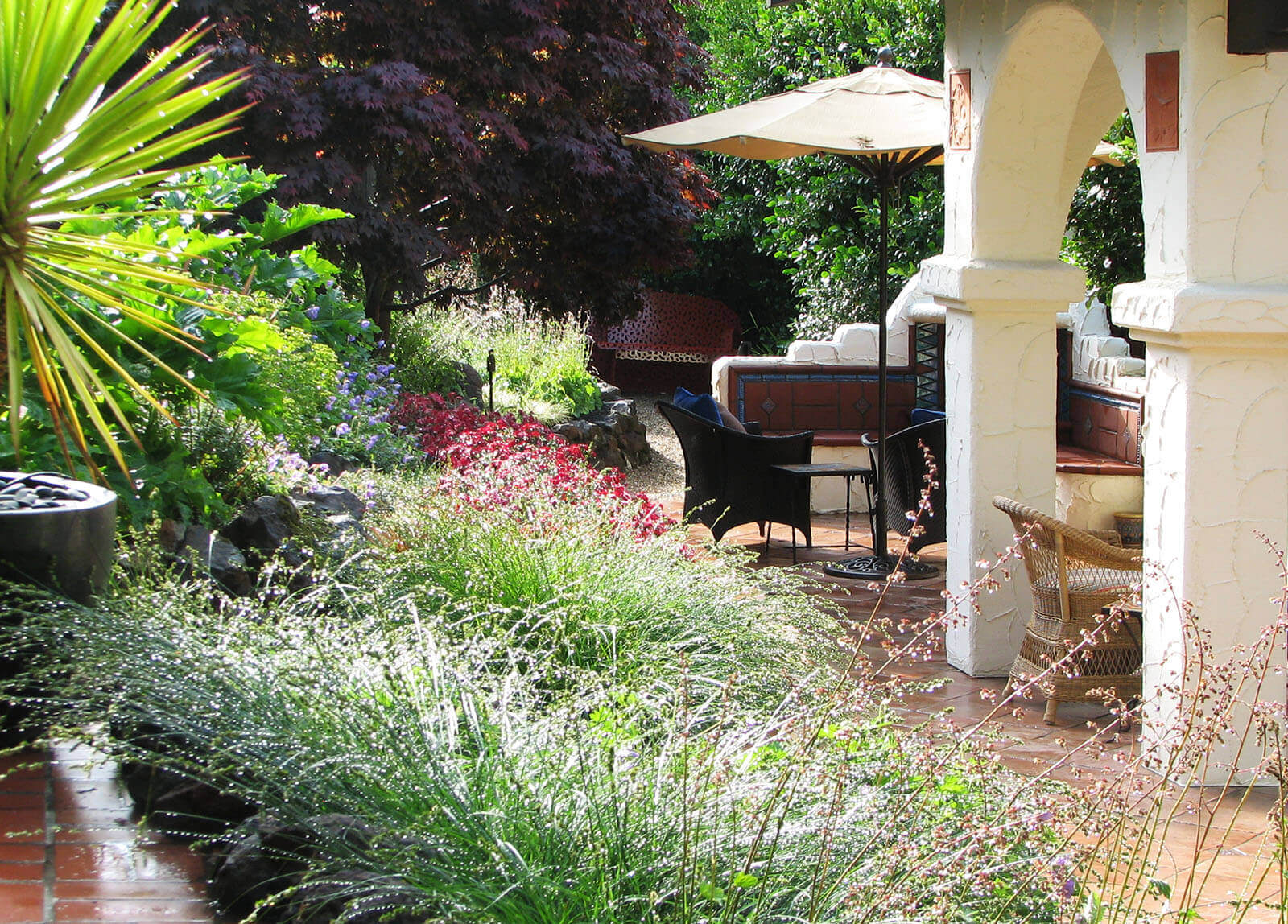 Diverse and colorful garden surrounding a shaded brick tile patio