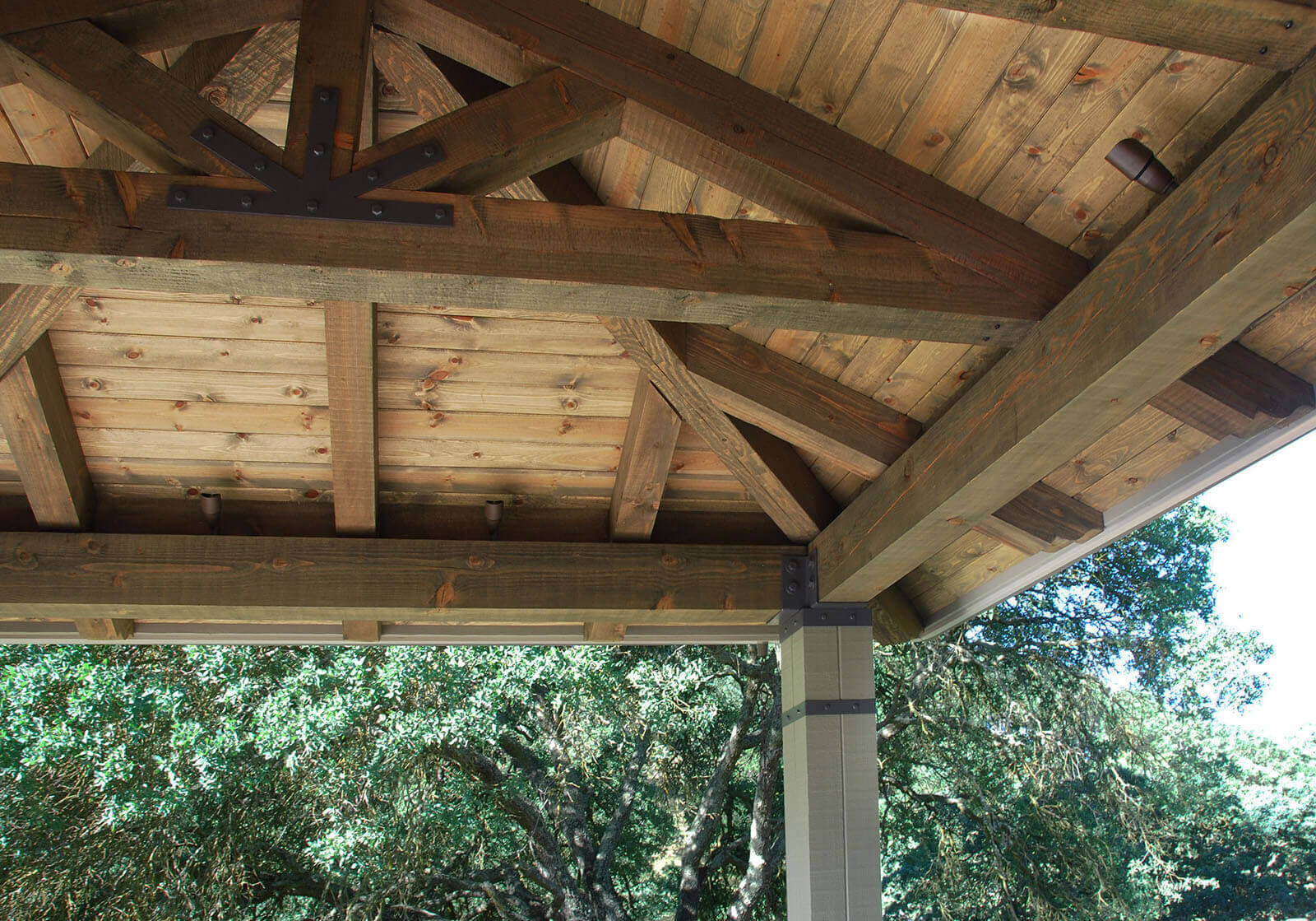Interior view of pergola roof with custom carpentry details and four-post iron-wrapped wood columns