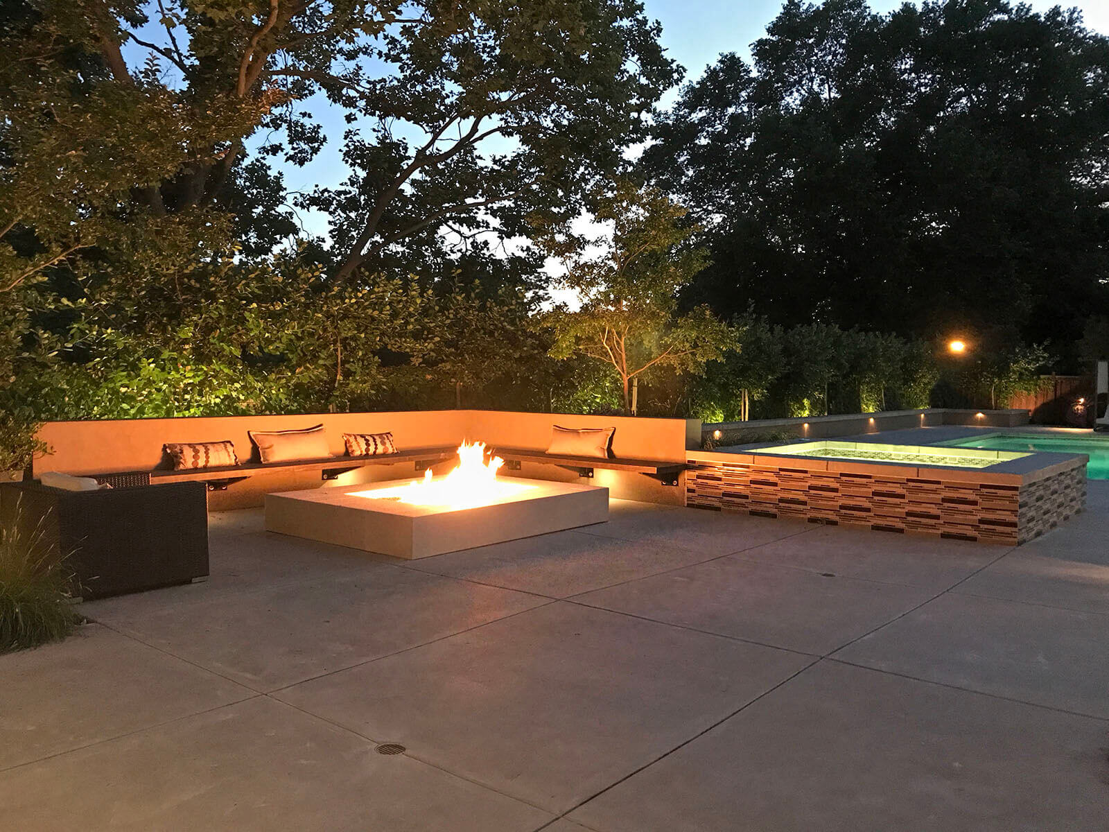Contemporary minimal concrete fireplace with wrap-around seating on stone patio