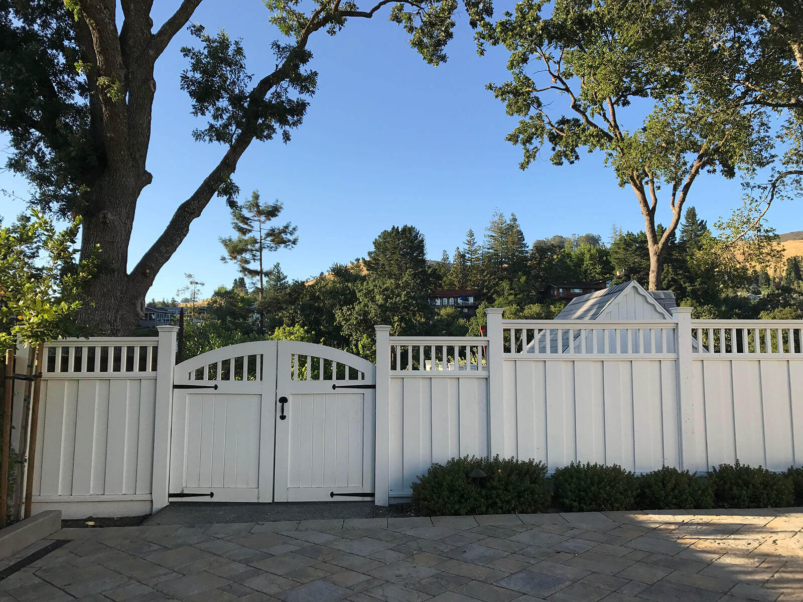 Tall white stepped privacy fence with curved double gate