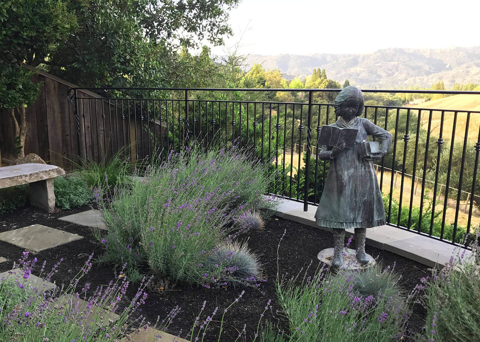 Garden with statue of little girl reading books, in front of lovely valley view