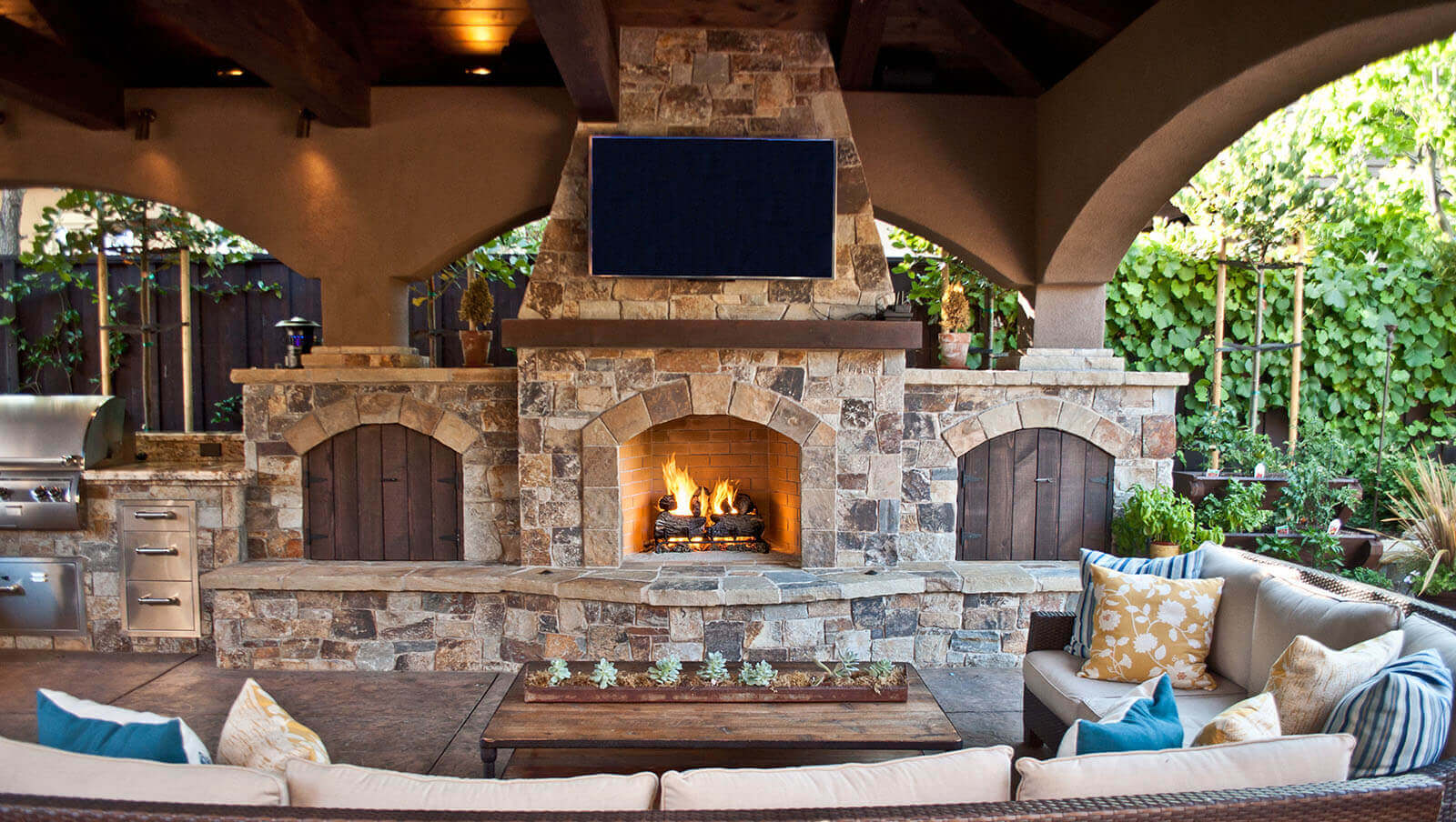 Covered patio with stone tile fireplace and storage area with lounge area and TV