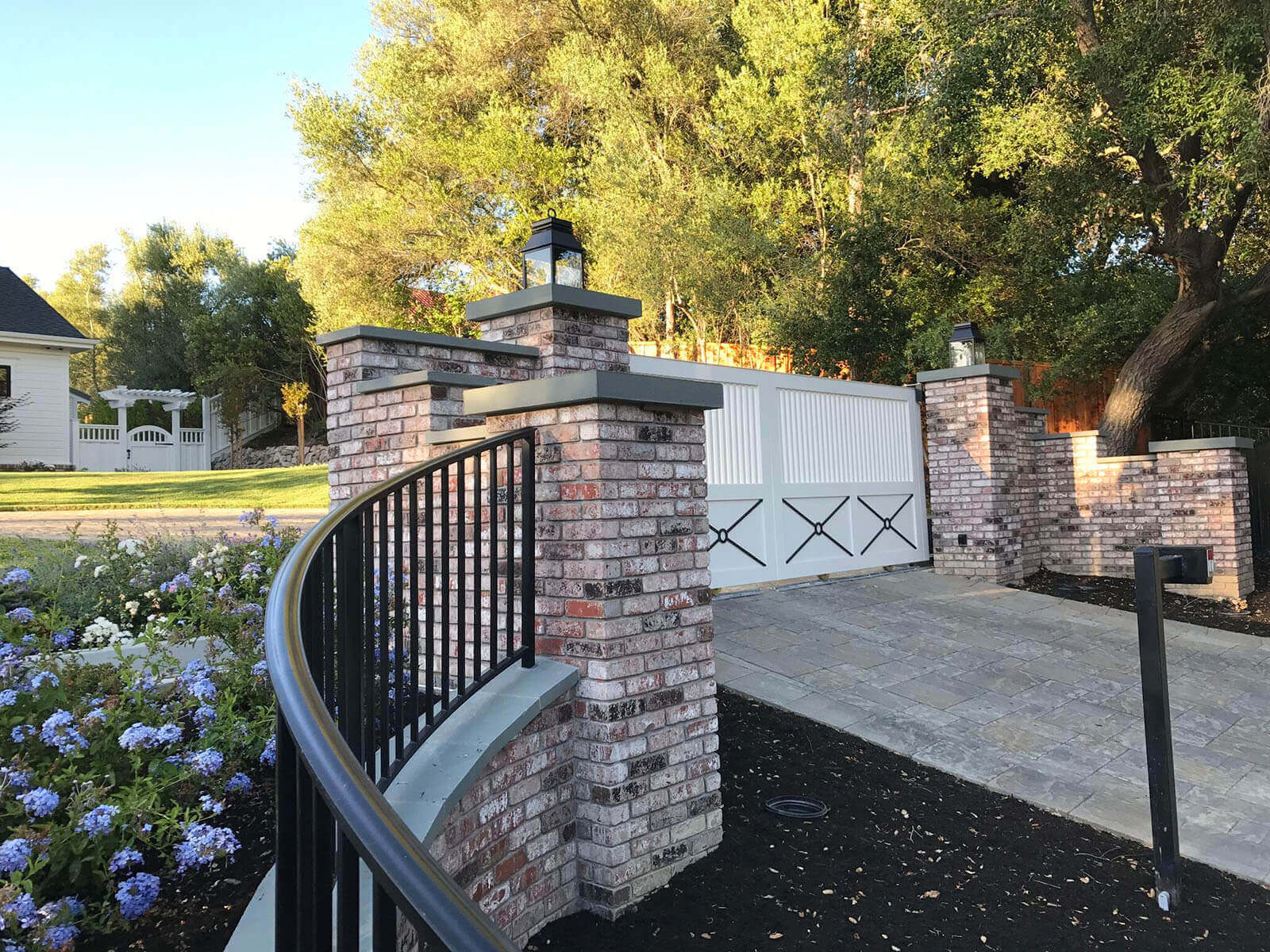 Brick and wrought iron border fence with custom barn-style driveway gate