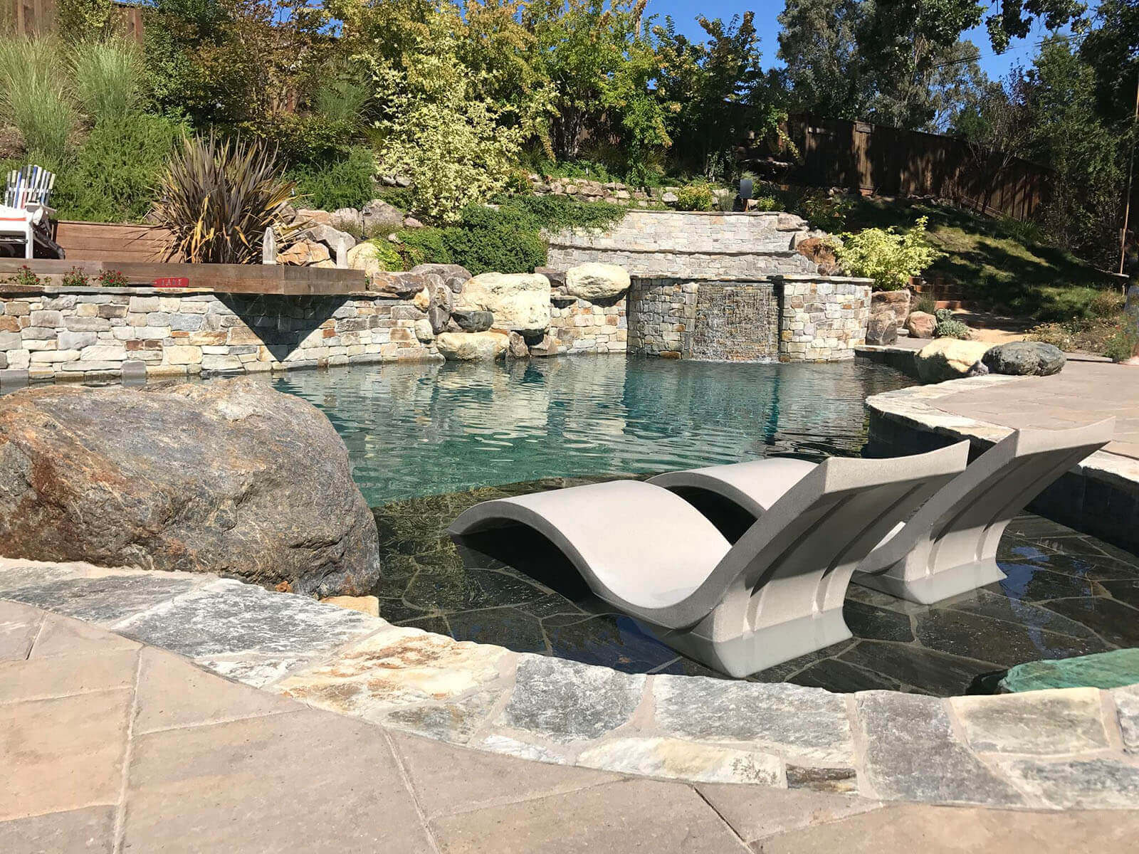 Stone accented pool with Baja shelf lounge, elevated spa, and 'dock' deck