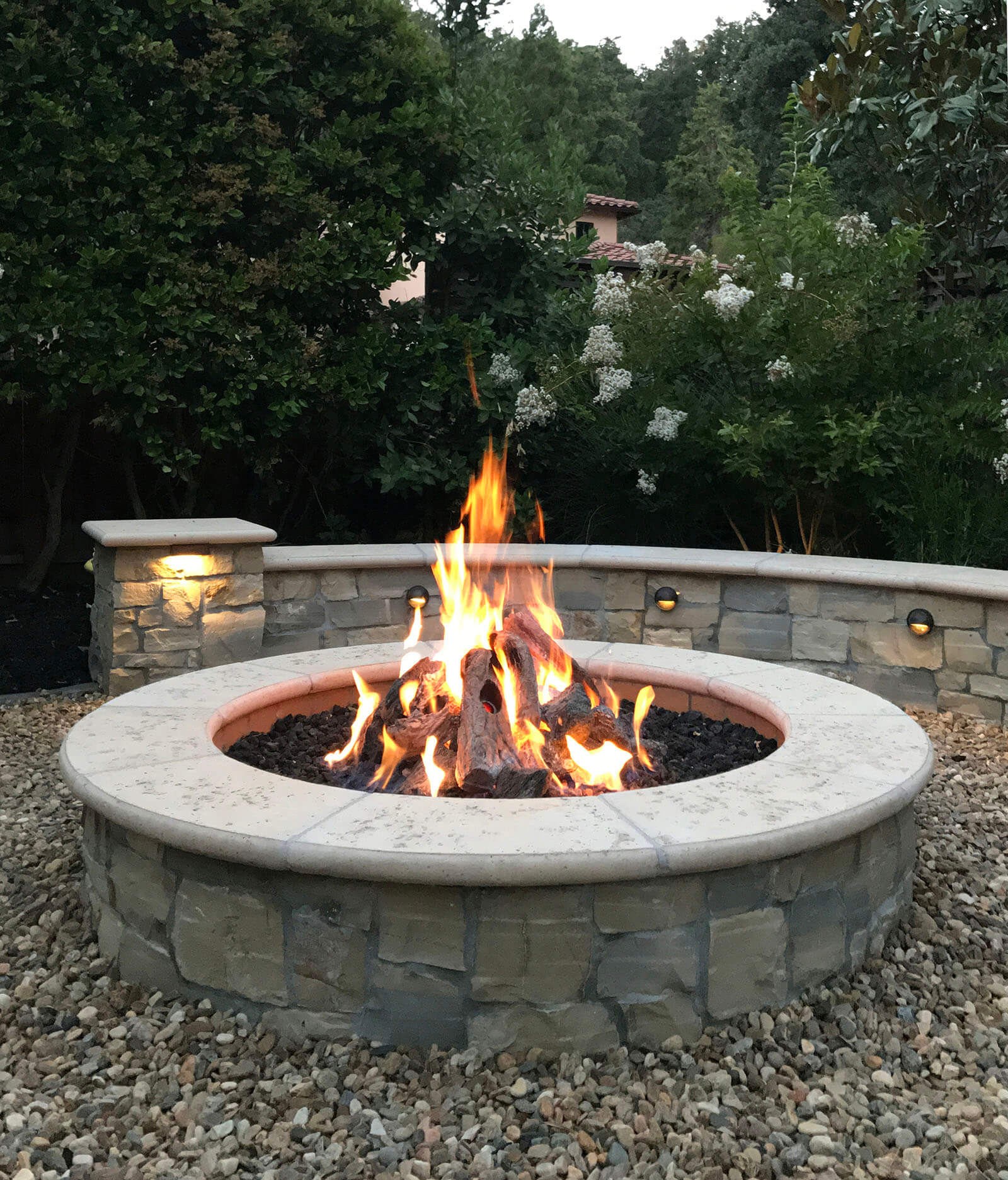 Rounded natural fireplace with stone bench and gravel surrounding area and stone walkway - Closeup shot