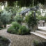 Rock-lined shaded gravel pathway leading from stone tile stairs to fire pit in back