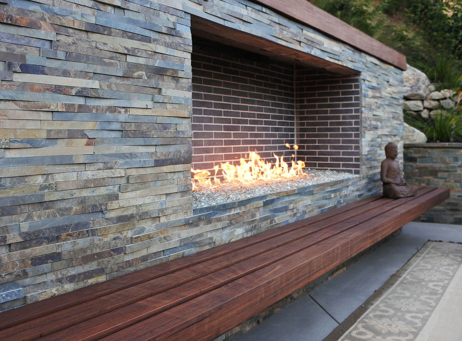 close up of slate stone tiled mantle with broken glass fireplace and dark wood seating area