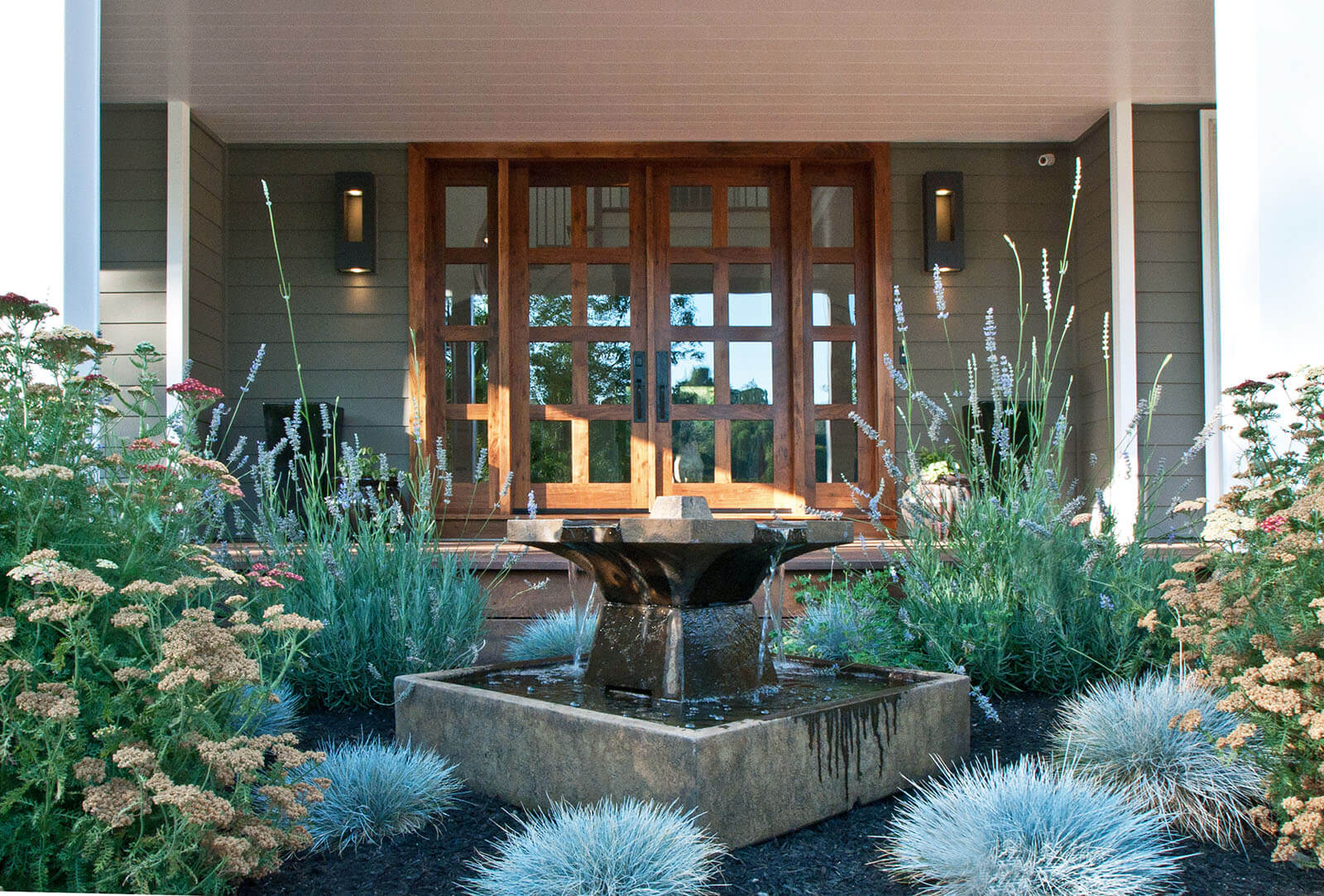 Centerpiece fountain with blue, green, and white grasses and flowers in front of glass ranch doors