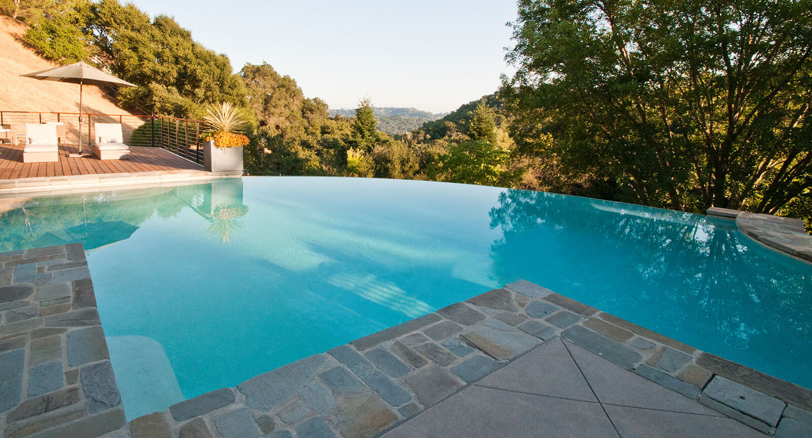 Edge-less pool looking over the valley, with stone patio flooring on the other side