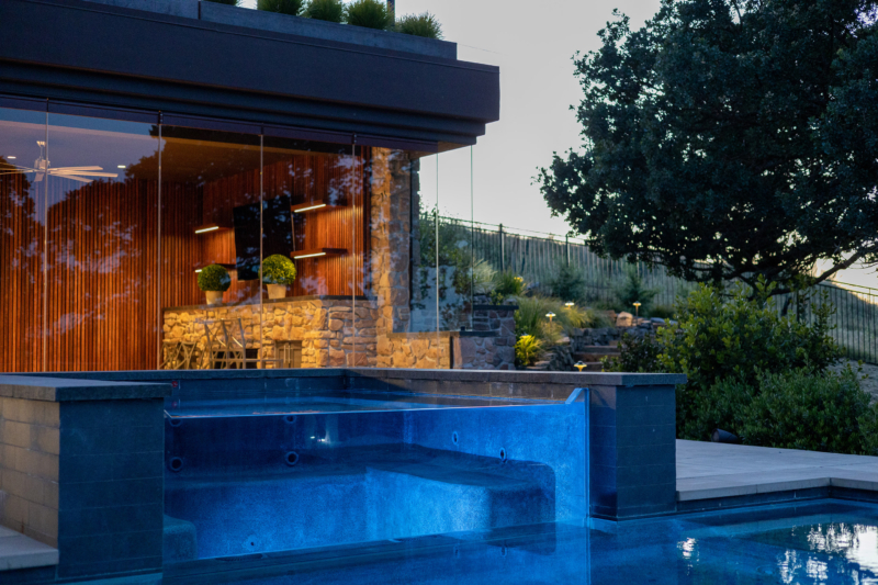 A contemporary pool and spa sits level with the bluestone patio, seamless in the expansive landscape.