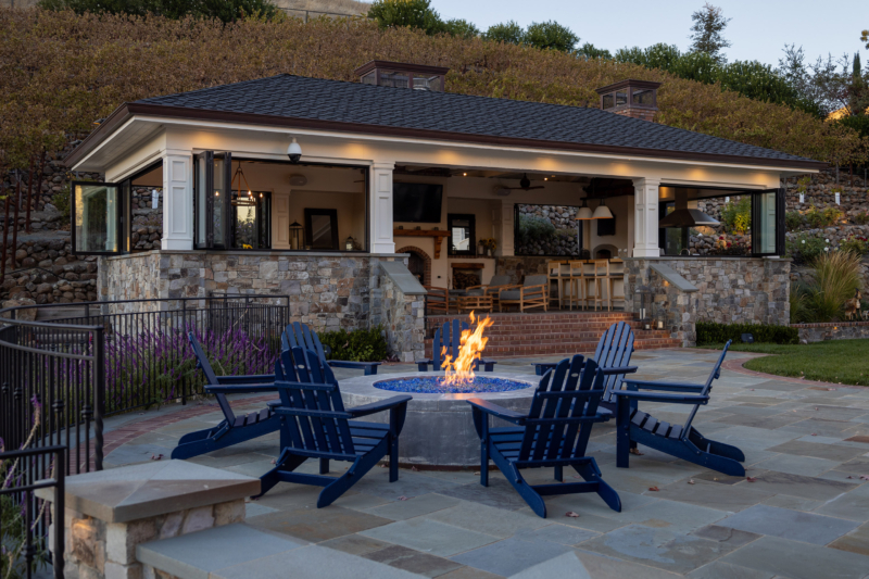 Indoor/outdoor living room looks out on pool and lawn