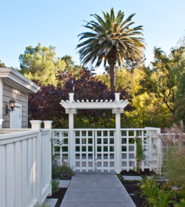 White wooden gate with an arbor provides a strong entrance into the landscape