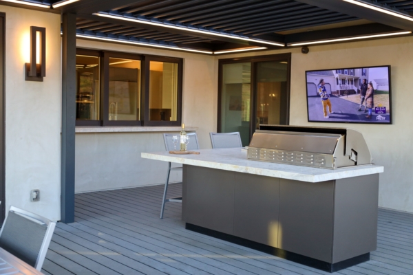 high-tech outdoor kitchen with flatscreen tv, remote controlled louvered pergola, and state of the art grill
