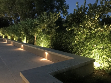 Modern seatwall with inset lighting, hedge behind with landscape uplighting