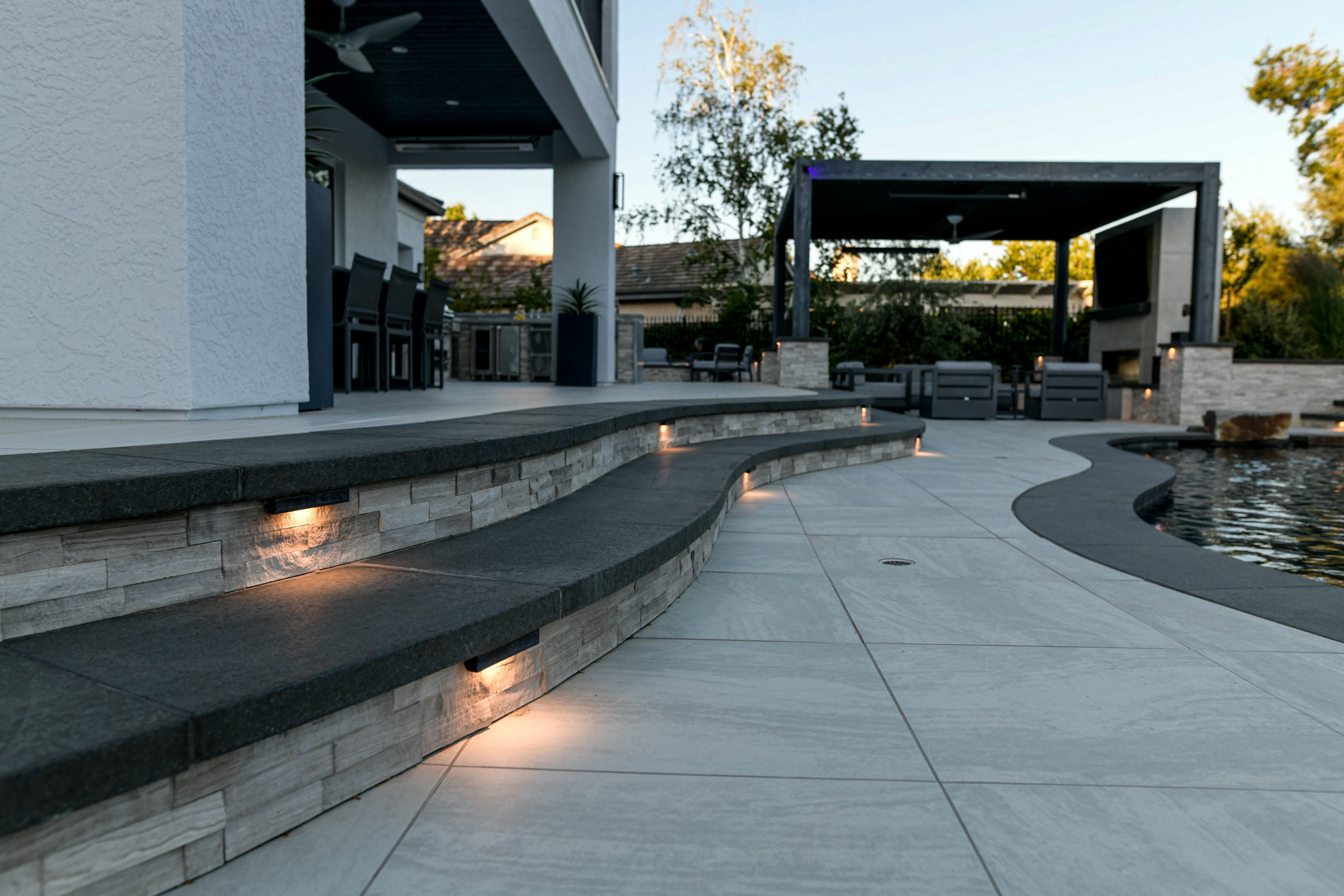 Contemporary curvilinear stone steps with tile patio and ambient lighting