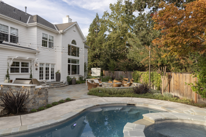 A rounded seat wall and chairs surround a firepit creating an attractive gathering space